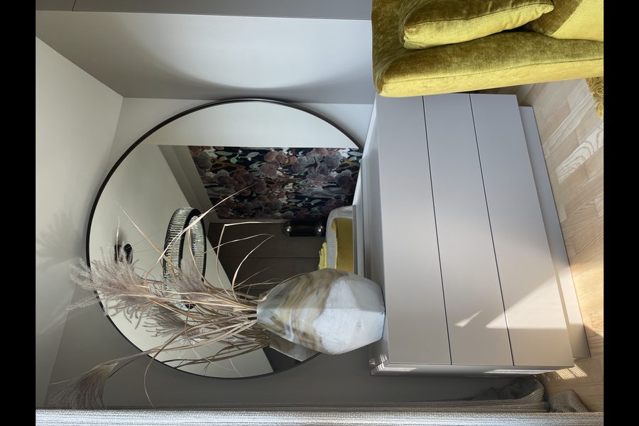 Umgebautes Gästezimmer mit rundem Spiegel und maßgefertigter Kommode